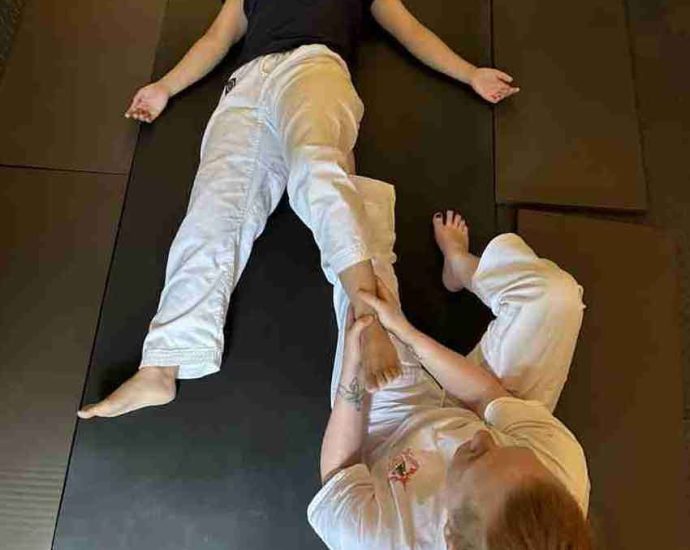 Therapist stretching client's leg on padded table